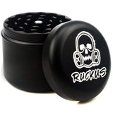 Black 4-piece grinder with skull logo and Ruckus text, includes custom Ruckus box